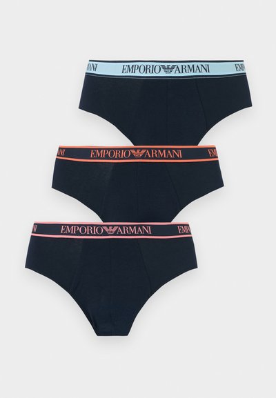 Τρία μαύρα ανδρικά εσώρουχα με λογότυπα Emporio Armani στις ελαστικές ζώνες μέσης σε μπλε, πορτοκαλί και ροζ χρώματα.