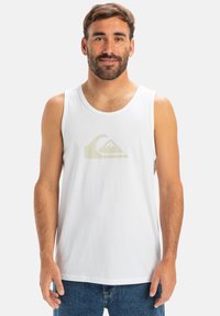 Hvitt bomullstank topp med rund hals, med en lys beige logo grafikk på fronten og et avslappet passformdesign.