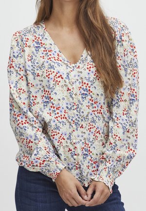 Bluse mit Blumenmuster in Creme, mit roten und blauen Blumen. V-Ausschnitt, Knopfverschluss und elastischen Bündchen. Leichter, weicher Stoff.