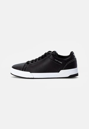 Czarny niskoprofilowy sneaker z białą podeszwą, czarnymi sznurowadłami i napisem „Court Touring” po boku, pokazany od zewnętrznej strony na jednolitym tle.