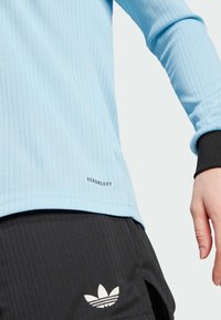 Light blue ribbed long-sleeve top with black cuffs, featuring "AEROREADY" branding. Paired with black ribbed shorts and white logo.