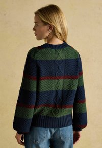 Pletený sveter s pruhmi v zelenej, námorníckej modrej a burgudskej farbe, textúrovaným vzorom a rebrovaným lemom so šnurovaním na chrbte.