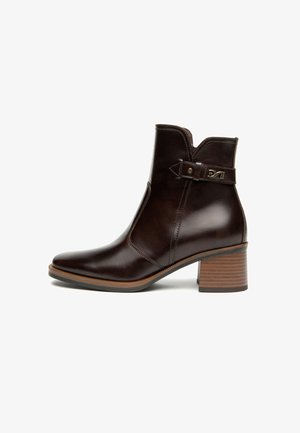 Braunes Leder-Absatzboot mit spitzer Zehenform, dekorativem Riemen und Schnallendetails sowie einem gestapelten Absatz. Glatte Textur mit minimalen Nähten.