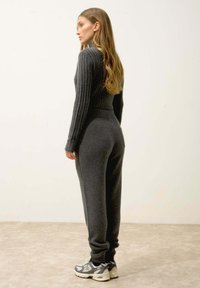 Tummanharmaa, ribattu pooloneule, joka on yhdistetty matching-housuihin. Pitkät hihat ja korkea elastinen vyötärö. Tennarit viimeistelevät asun.