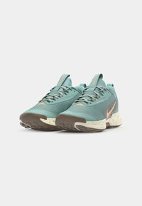 Chaussures de course turquoise avec une tige en maille texturée, semelle extérieure en caoutchouc marron et accents orange. Elles disposent d'œillets renforcés et d'une languette rembourrée.