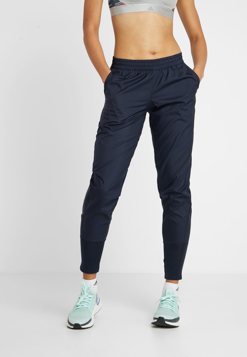 Navy lightweight joggers with an elastic waistband, tapered fit, side pockets, and ankle cuffs, paired with mint green athletic shoes.
