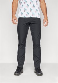 Černé kalhoty v slim fit, vyrobené z lehké tkaniny s hladkou texturou. Spárované s černými turistickými botami.