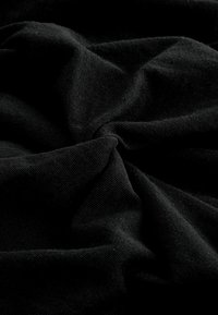 Tissu noir avec une texture douce, présentant des plis et des rides, mettant en valeur une finition lisse avec un léger éclat.