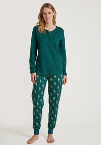 Groene katoenen top met lange mouwen en drie knopen, gecombineerd met bijpassende pyjamabroek met tapering, versierd met een patroon van herten en harten.