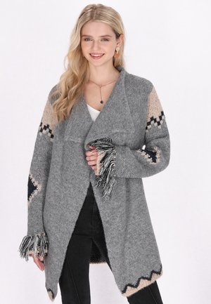 Cardigan grigio a maglia con apertura frontale, maniche a fantasia beige e nere in contrasto, e dettaglio di frange sui polsini. Texture morbida.