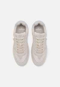 Beige suede sneakers with a round toe, perforated detailing on the vamp, and light grey accents at the heel and tongue.