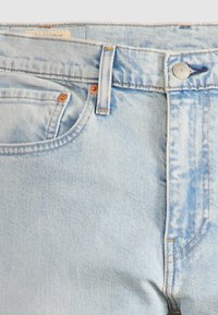 Lyseblå denimjeans med et klassisk fem-lommers design, kobberknapper og en subtil slitt tekstur i stoffet.