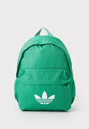 Sac à dos en tissu vert avec poche avant zippée et logo blanc Adidas trefoil sur la poche, présenté sur un fond uni.