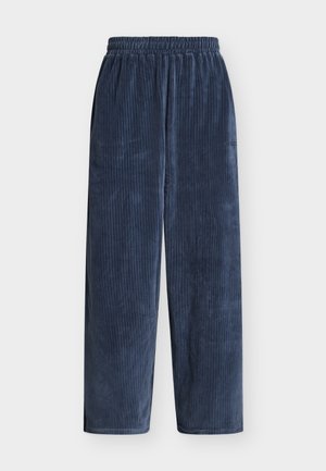Pantalones de pana azul marino con un corte holgado, que presentan costillas verticales, una cintura elástica y un bolsillo lateral. Textura suave.