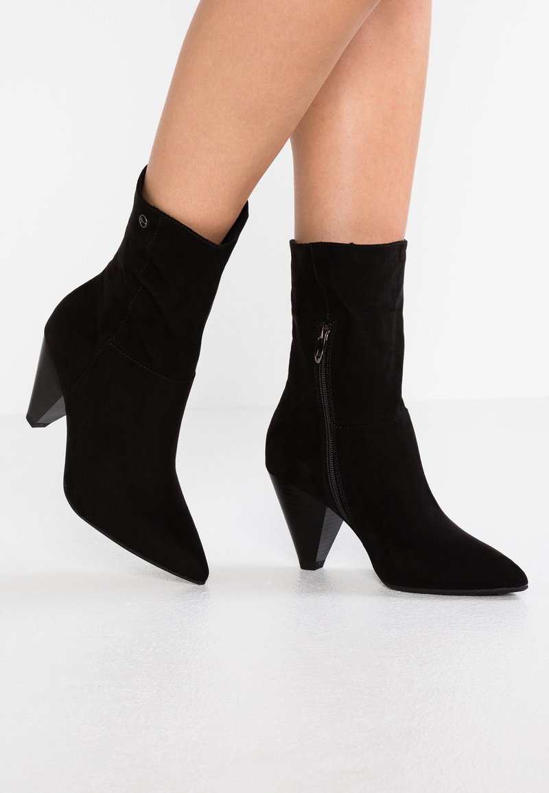 Bottines en daim noir avec bouts pointus, talons coniques et fermetures éclair latérales. Texture douce avec une finition propre et soignée.