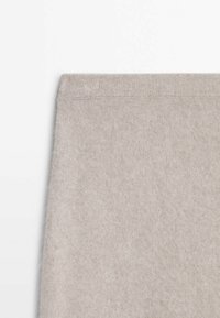 Grå strikket sweater lavet af blødt stof med en glat overflade og en ribbet halsudskæring. Enkel og minimalistisk design.