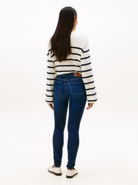 Haut à manches longues rayé en blanc et marine, associé à un jean skinny bleu foncé. Les caractéristiques notables comprennent une coupe décontractée et un dos uni.