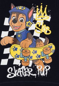Tegneseriehund på skateboard med gul plattform som har blå poter. Bakgrunnen har et svart og hvitt rutemønster. Tekst: "Skater Hunden."