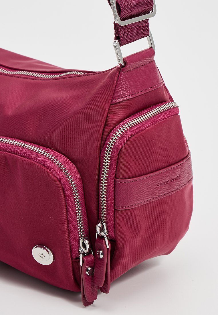 Rote Nylon-Schultertasche mit mehreren Reißverschlussfächern, strukturierten Akzenten und einem verstellbaren Tragegurt. Mit silberner Hardware.