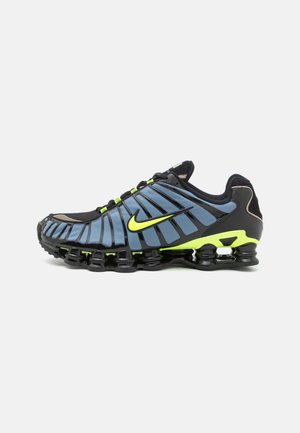 Chaussure de course Nike noire et bleue avec des accents jaune néon et une semelle noire segmentée, vue de profil sur un fond blanc.