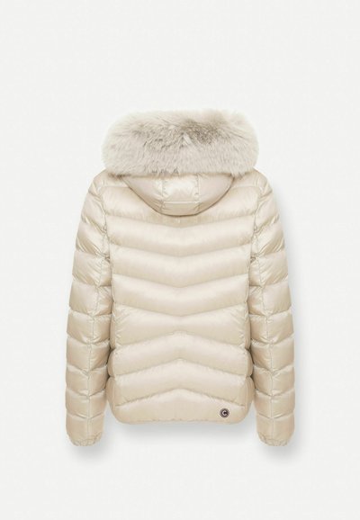 Veste d'hiver matelassée beige clair avec surpiqûres en chevron et capuche bordée de fourrure douce et duveteuse, vue de dos.