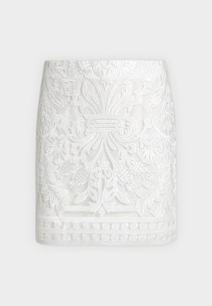 Λευκή μίνι φούστα με περίτεχνη ανάγλυφη κεντητική με λουλούδια και φύλλα, με διακοσμητική ρεβέρ και εφαρμοστή σιλουέτα.