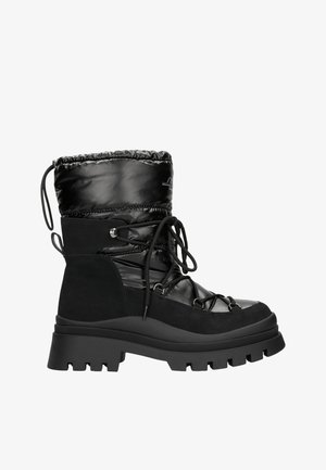 Bottines noires à cheville présentant un mélange de matériaux synthétiques brillants et de suède mat. Le design comprend une semelle épaisse et robuste ainsi que des détails de lacets.