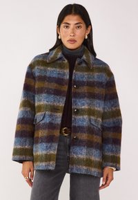 Giacca in misto lana a quadri con strisce blu, verdi e borgogna, chiusura a bottoni e tasche laterali. Collo classico e vestibilità comoda.