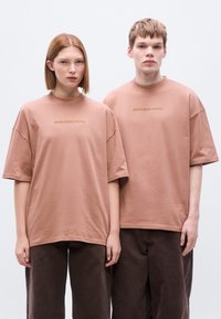 Ανδρικά t-shirt μακριάς γραμμής με κοντά μανίκια σε ροζ βαμβακερό ύφασμα, με στρογγυλή λαιμόκοψη και την επιγραφή "BROKE SINCE MILANO" σε χρυσή γραμματοσειρά.