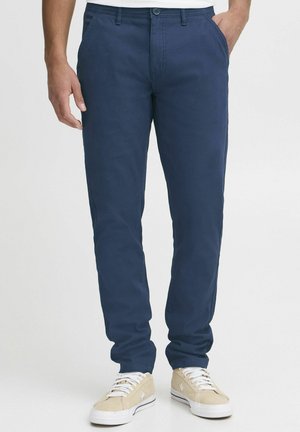 Mörkblå chinos, slim fit, tillverkade av bomullsblandat tyg. Har framfickor, subtila sömmar och en knappstängning i midjan.