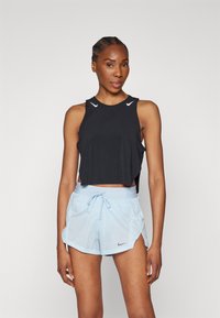 Top corto sin mangas negro con acentos de logo blancos, combinado con pantalones cortos de tiro alto azul claro con cordón, que presentan una abertura lateral y detalle de logo.