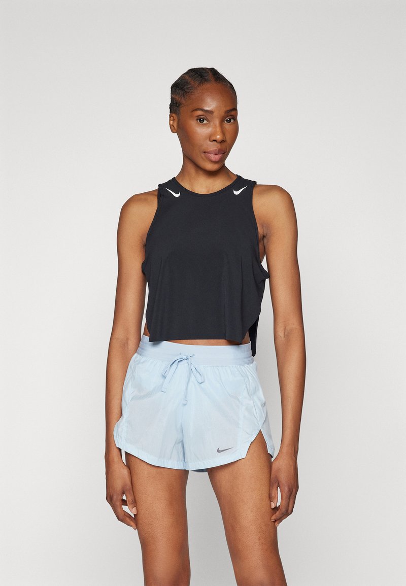Top corto sin mangas negro con acentos de logo blancos, combinado con pantalones cortos de tiro alto azul claro con cordón, que presentan una abertura lateral y detalle de logo.