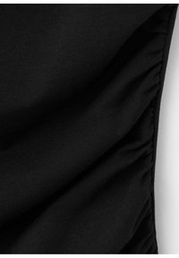 Tissu noir avec un détail élastique froncé le long d'une couture verticale, montrant la texture et les plis sur un fond blanc.