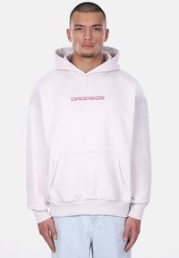 Helle rosa übergroße Kapuzenjacke mit Kordelzugkapuze, Fronttasche und "DROPSIZE"-Logo in dunkelrosa. Glatte Textur, gerippte Bündchen und Saum.