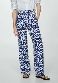 Pantalon à jambes larges en bleu et blanc, présentant un motif de feuilles tourbillonnantes, fabriqué en tissu léger avec des poches latérales et une taille haute.