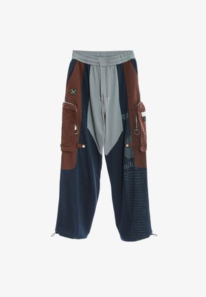 Pantalones cargo en azul marino y gris, con acentos marrones, múltiples bolsillos con cremallera, cintura elástica y detalles estampados.
