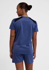 Camiseta deportiva de manga corta en azul con detalles en negro, fabricada con un tejido transpirable. Presenta un escote redondeado y paneles en los hombros para mayor movilidad.
