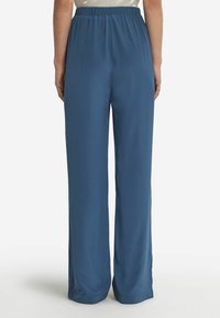 Blå vida byxor med elastisk midja. Tillverkade av ett slätt tyg med en något glänsande textur, designade för en avslappnad passform.