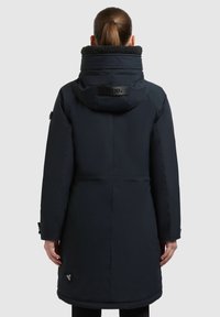 Marineblå parka med høj krave, struktureret fleeceforing og justerbare cuffe. Har branding på ryggen og detaljer i sidelommen.