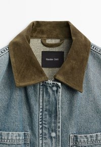 Denimjas met een bruine corduroy kraag, contrasterende blauwe stof, borstzak en een zwart label met de merknaam Massimo Dutti.
