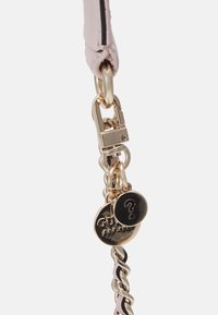 Chaîne en or avec cuir rose tissé, attachée à un fermoir en or et deux breloques en or, l'une avec un point d'interrogation et l'autre avec le texte "GUESS".
