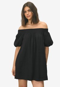 Zwart off-shoulder jurkje met pofmouwen, gestructureerde stof, ontspannen pasvorm en elastische smocking bij de halslijn. Halverwege de dij lengte.