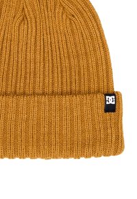 Berretto lavorato a maglia giallo senape con texture a coste e risvolto. Presenta un piccolo etichetta nera con logo sul lato.