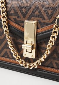 Borsa a tracolla con motivo marrone, caratterizzata da una catenella dorata e una chiusura metallica rettangolare. Superficie testurizzata con dettagli in pelle nera e beige.