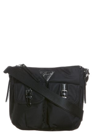 Zwarte crossbodytas met verstelbare band, twee voorvakken met gespen en een driehoekige logopatch op de flap.