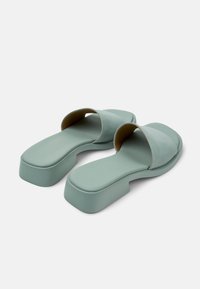 Green, flat slide sandals with a wide strap and a platform sole. Made from smooth suede-like material, featuring rounded edges and minimal detailing.