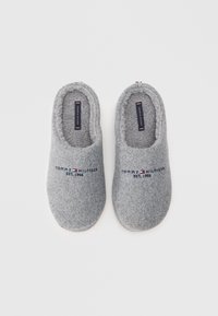 Papuci gri din fetru cu interior moale, având brodat pe față textul și logo-ul "TOMMY HILFIGER EST. 1985". Design cu vârf rotund.
