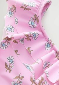 Tissu froncé rose avec un motif floral présentant des fleurs blanches et des centres bleus, avec des tiges et des feuilles brunes, affichant une texture lisse.