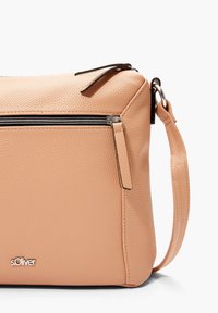 Pomarańczowoczerwona torebka ze skóry o teksturowanym wykończeniu, z przednią kieszenią na suwak i odczepianym paskiem. Widoczny metalowy akcent z logotypem.