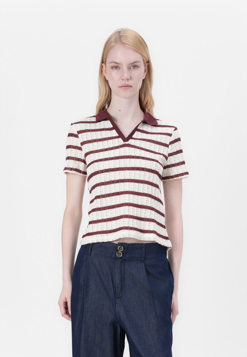 Kurze Ärmel, gestricktes Poloshirt in Creme mit burgunderfarbenen horizontalen Streifen, mit V-Ausschnitt und kontrastierendem Kragen. Getragen mit dunklen Hosen.
